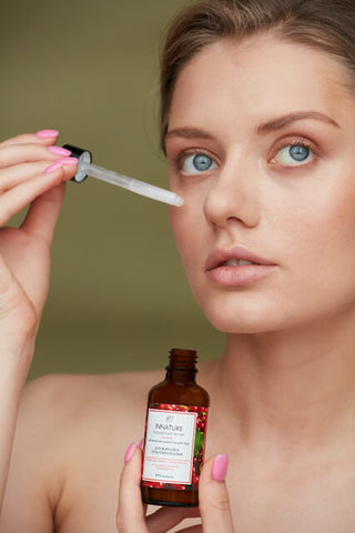 Young blonde woman with blue eyes putting on skincare serum