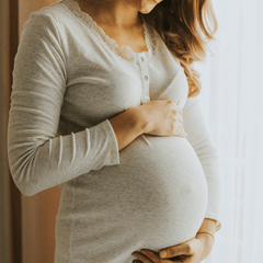 Close up of a round pregnant belly and woman holding it