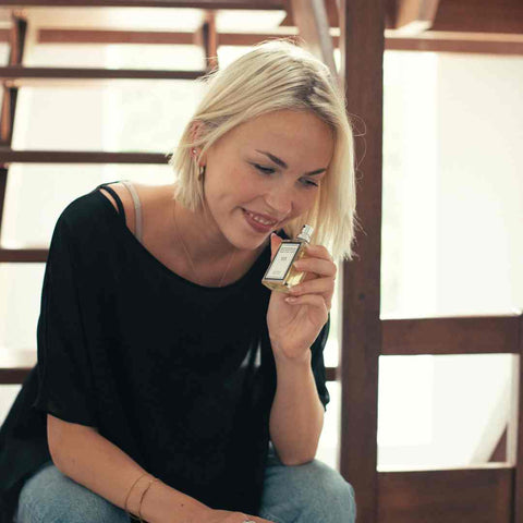 Image of a woman holding a perfume from The Essence Vault to her nose, is perfume a good gift for mother's day?