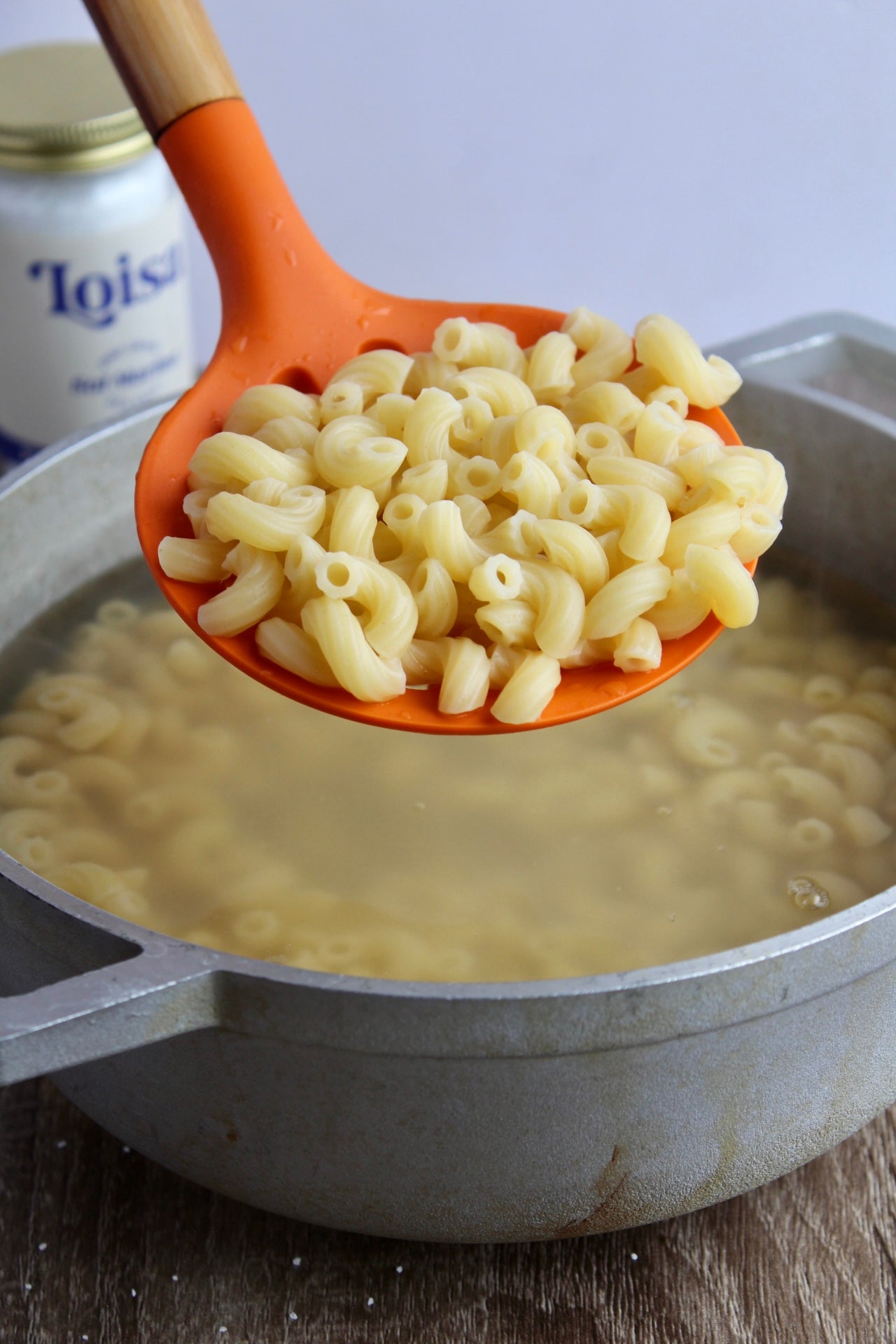 Macaroni getting spooned out of pot with skimmer
