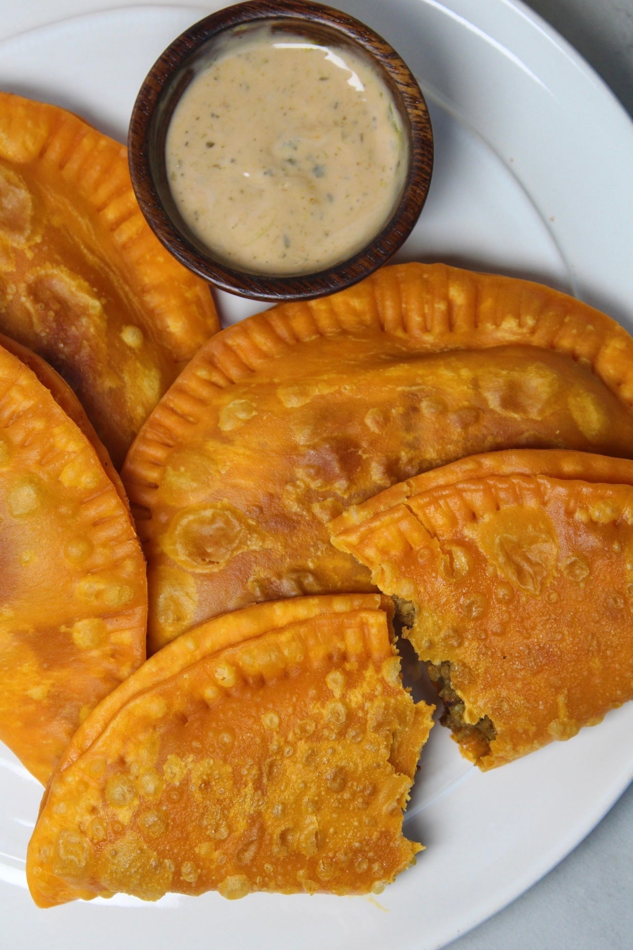 Empanadas on a plate with sauce on the side