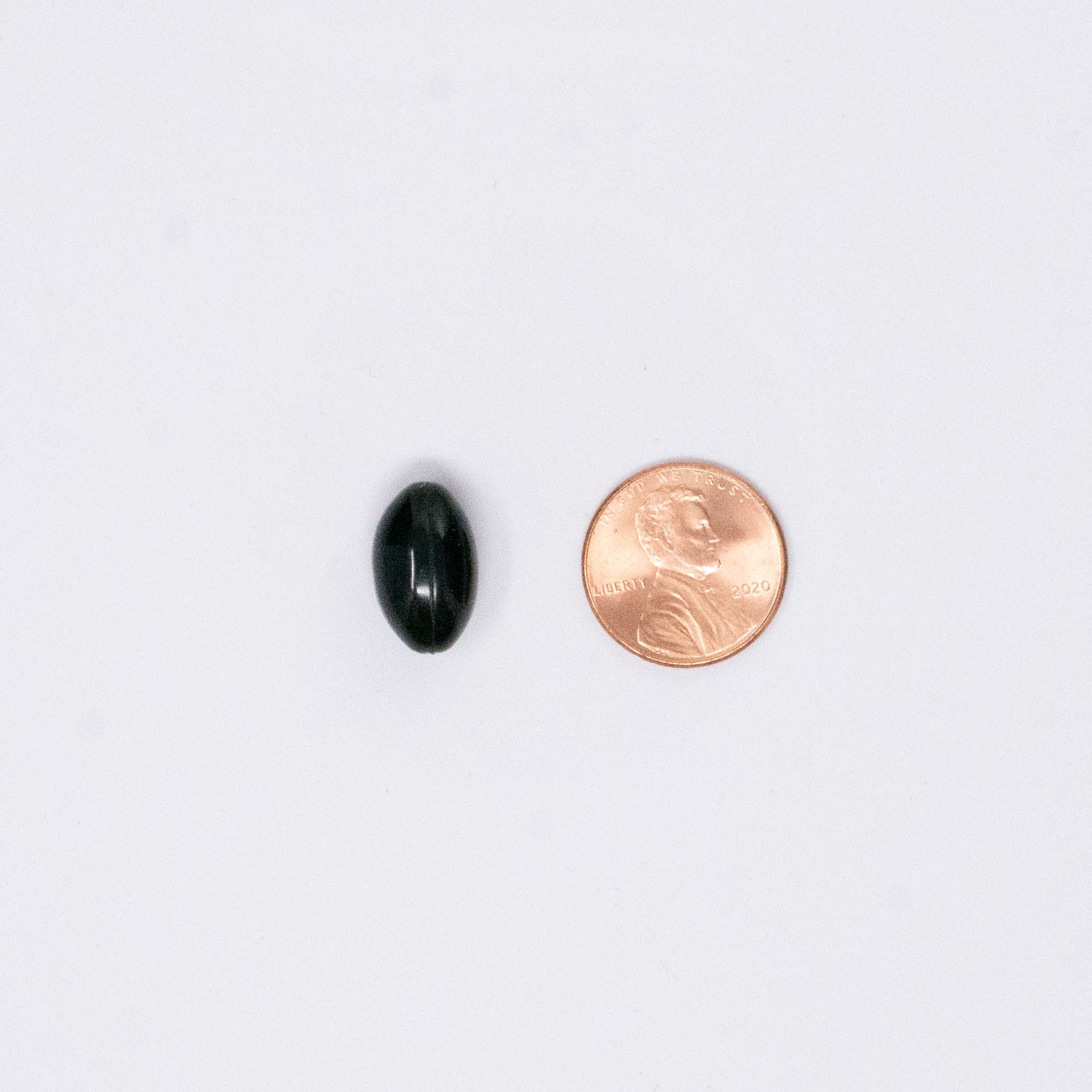 black vitamin Astaxanthin next to a penny