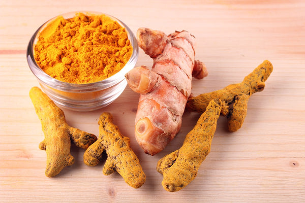 a bowl of tumeric powder and ginger roots 