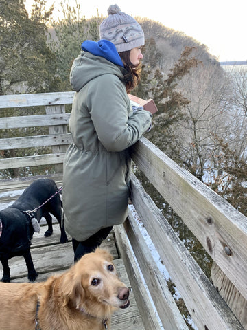Golden retriever Bella on a hike with woman in gray hat and black lab