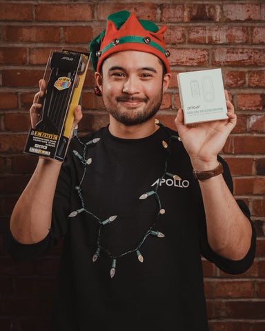a man is holding apollo products and wearning a christmas elf hat
