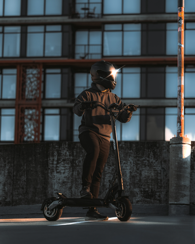 A man in black clothes and helmet stands on an the Apollo phantom e-scooter