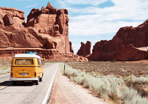 car riding on road with canyons in the horizon 