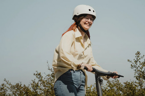 women smiling while riding e-scooter outside in summer