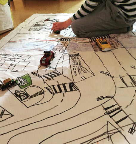 child playing on hand-drawn neighbourhood mat