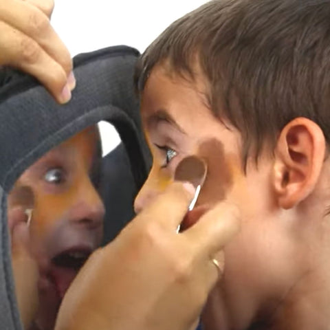 Kids looking in mirror while getting face painted