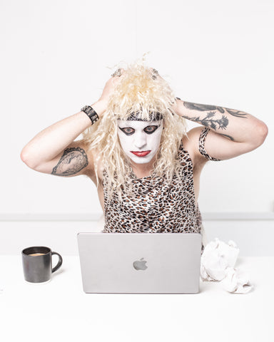 Person wearing corpse makeup in front of a laptop