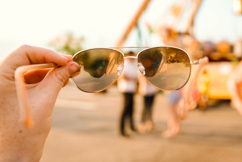 Person holding sunglasses up to the sun