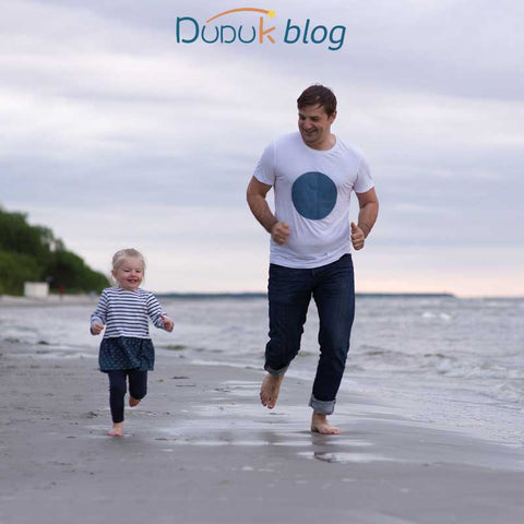 Papa corriendo con niño en la playa mientras lop cuida y le enseña a correr siempre más lejos