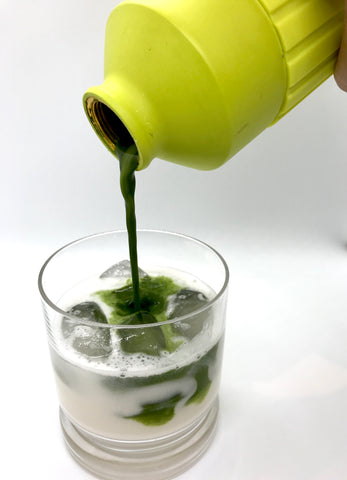Pour matcha into glass with milk and ice for iced green tea summer drink
