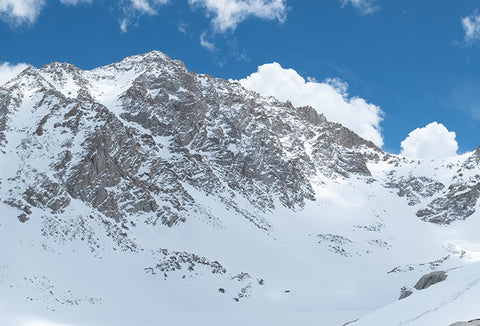 The snowy Sierra Mountains with a bright blue sky behind them.