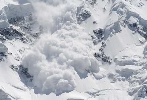 An avalanche of snow rolling down a hill.