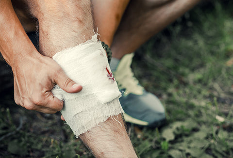 A man wrapping his wounded leg with white bandages.