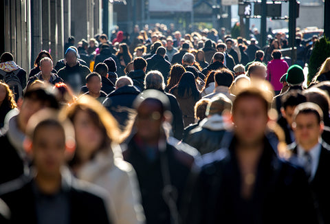 A crowd of people walking on a busy sidewalk.