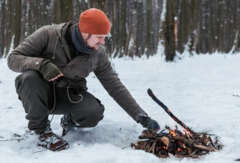 Man building a fire in the snow.