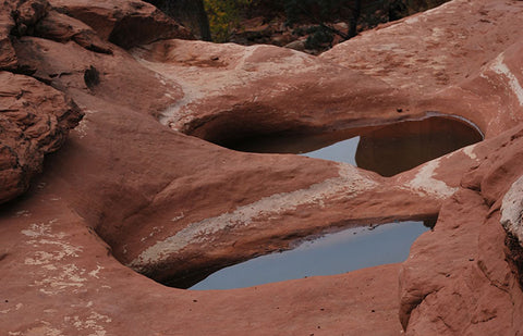 Red rocks carved out and filled with water.