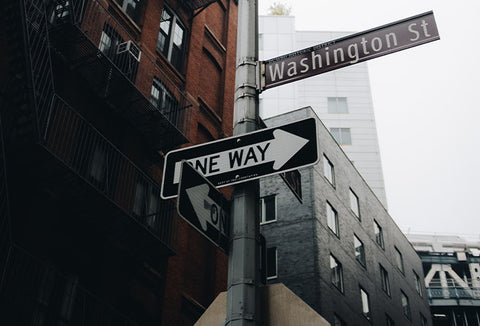 Several street signs on a corner of a big city.