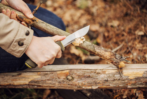 Person using a knife to cut wood.