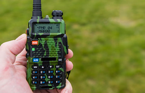 A perso holding a handheld radio with a camouflage pattern.
