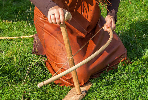 A woman lighting a fire using the bow drill method.