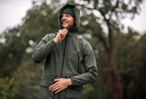 Man zipping up a jacket in the outdoors.