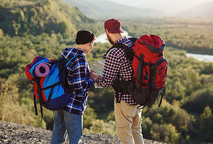 Two people standing on a cliff edge in hiking gear going over an emergency plan.