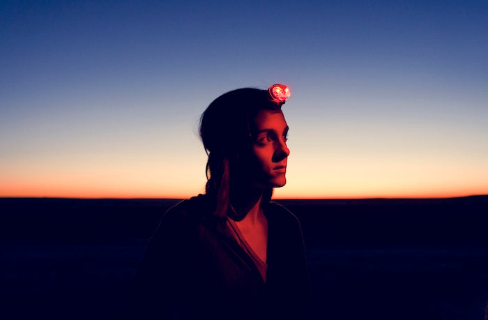 woman outside in a headlamp at sunset