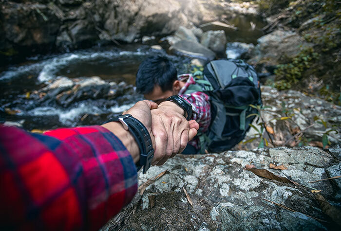 Someone grabbing a man's hand to stop him from falling off a cliff.