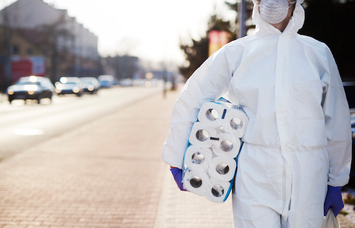 person in protective suit carrying toilet paper