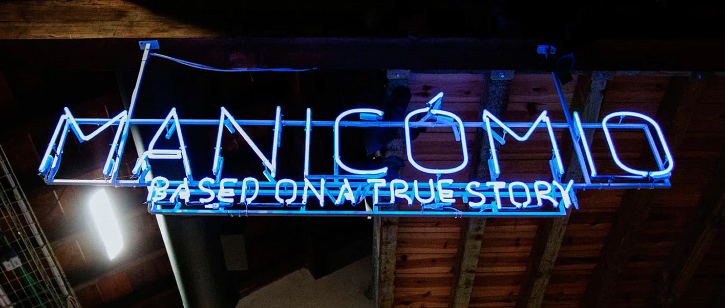 Neon sign in blue and white reads Manicomio for custom shoes project.
