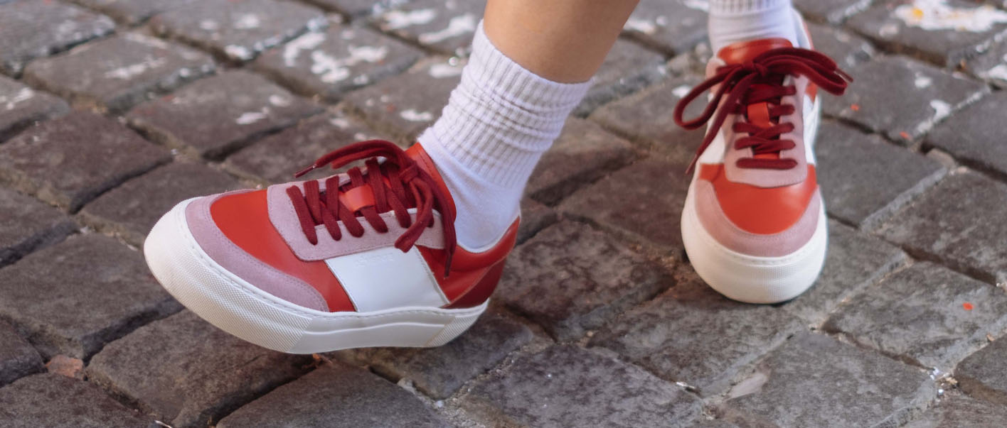 A person wearing low top red and white sneakers, custom-made for women.