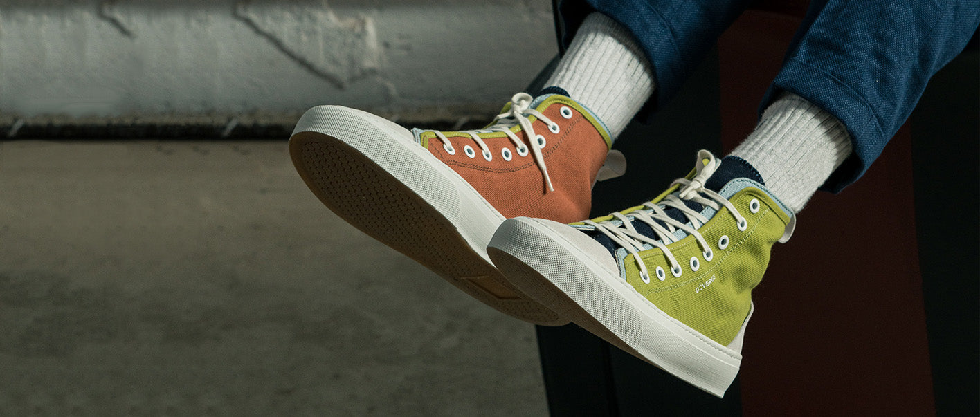 A person wearing vibrant high top sneakers sitting on a bench. The sneakers are customized men's shoes.