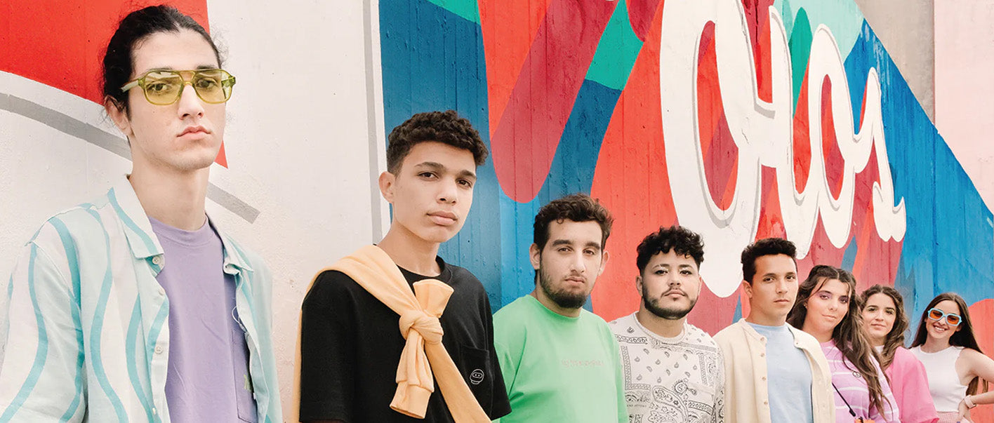 A group of young people standing in front of a wall, wearing custom shoes.