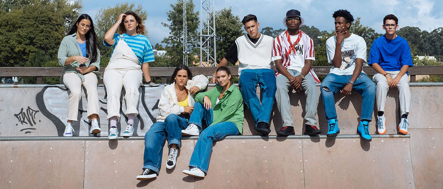 A group of young people sitting on top of a skateboard ramp, wearing custom shoes.