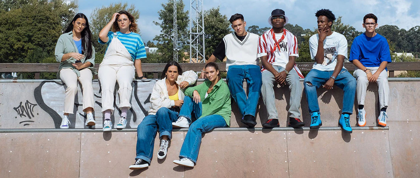 Un groupe de jeunes gens assis au sommet d'une rampe de skateboard, portant des chaussures personnalisées.