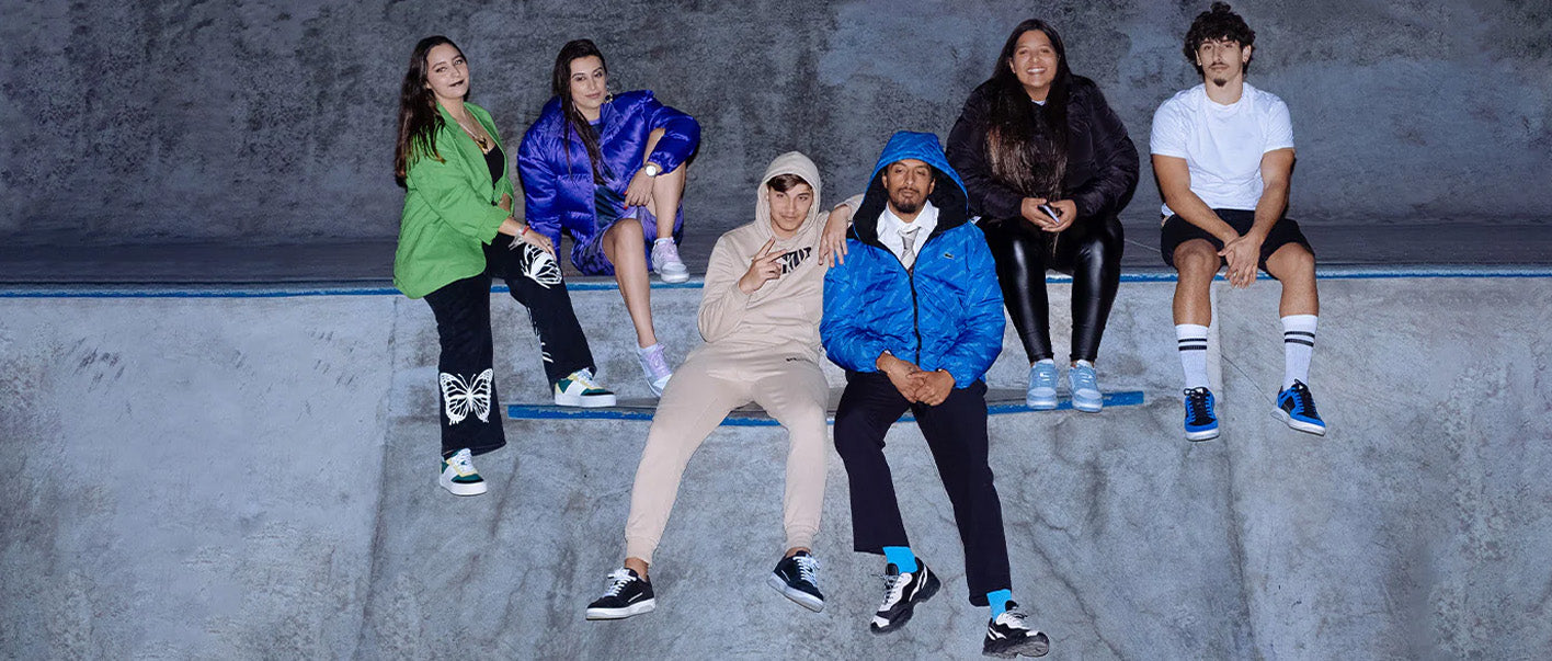 A group of young people sitting on a skateboard, wearing custom shoes.