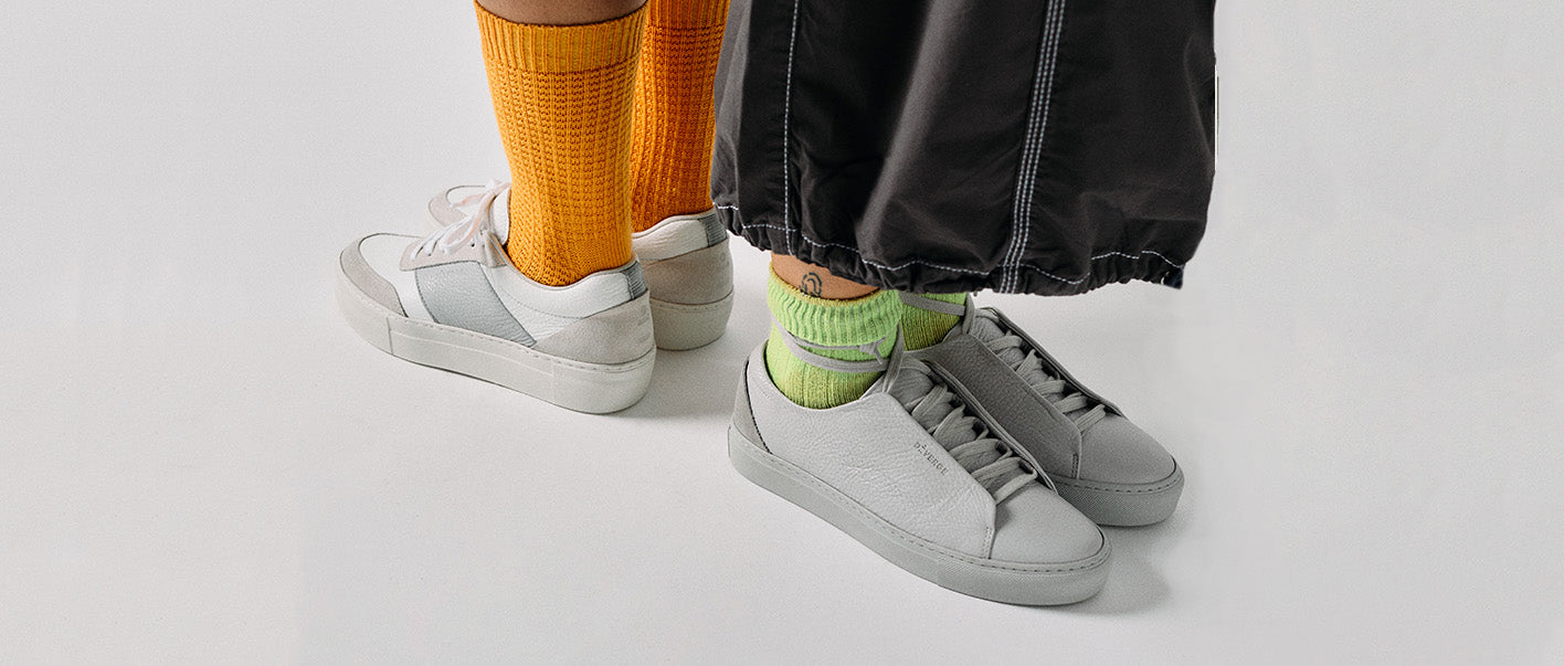 Weiße sneakers und gelbe Socken an den Beinen, Top-Seller Custom-Schuhe.