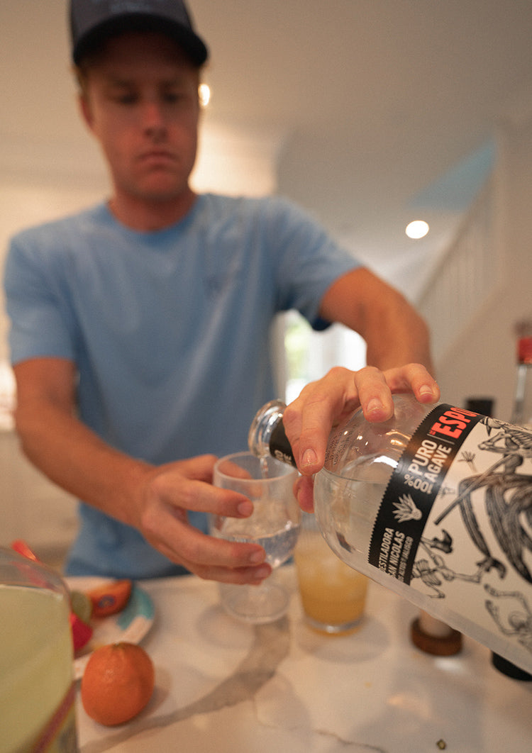 man pouring tequila in glass for margarita drink