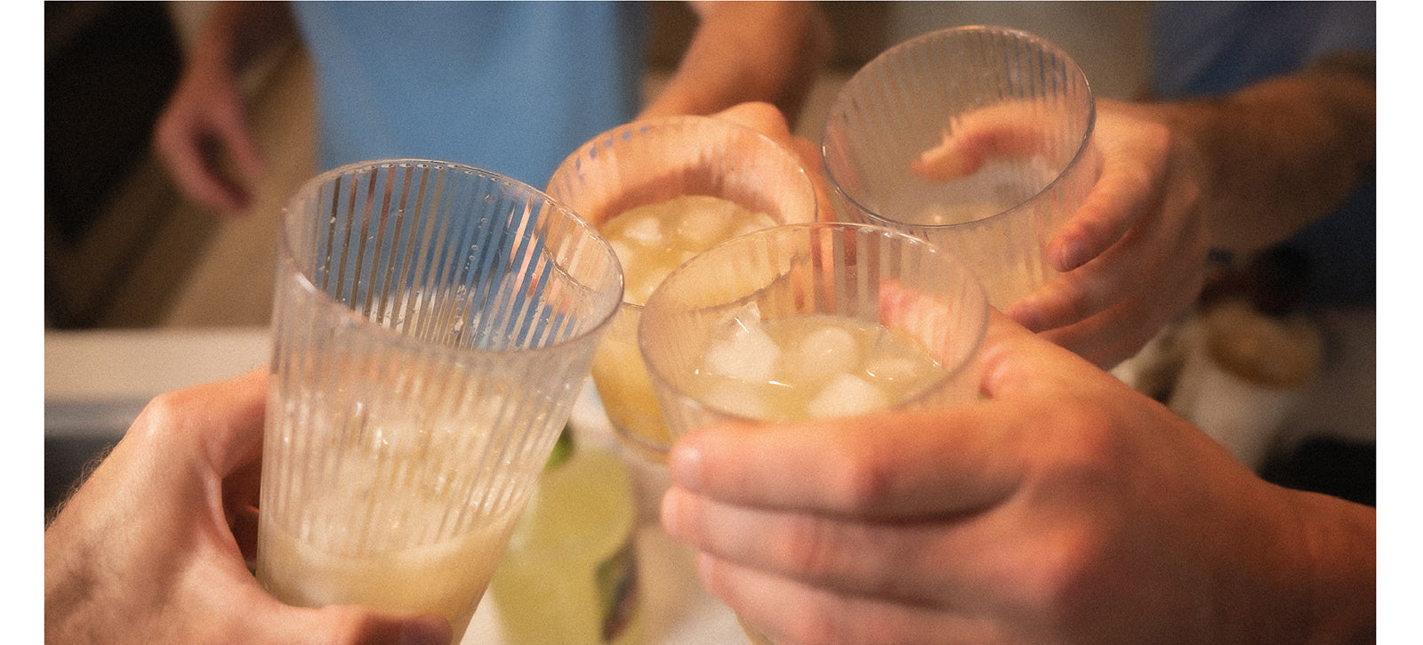 four people tapping margarita glasses together for cheers