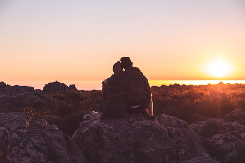 A couple sitting on top of a boulder