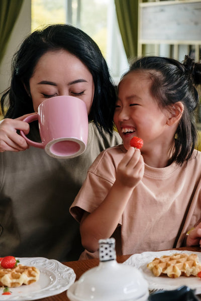 Mum drinking coffee and having breakfast with child