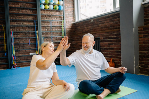 A senior couple sitting on an exercise mat