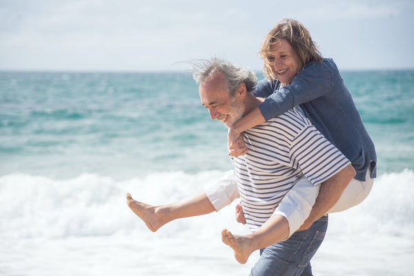 A senior couple smiling and strolling along the beach