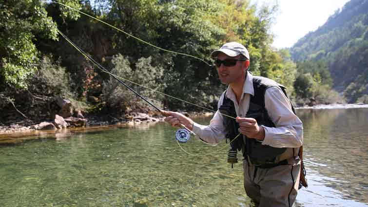 Man using both arms to cast fly rod