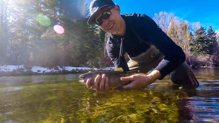 Fly Fishing waders in river on man catching rainbow