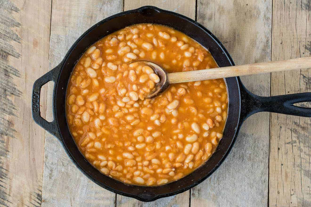 baked beans in pot with a spoon.